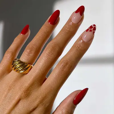 Oxblood red manicure with one large heart French tip and one multi-heart French tip