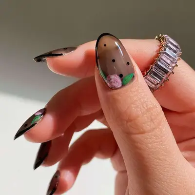 Sheer black manicure with French tip, polka dots, and pink rose detail