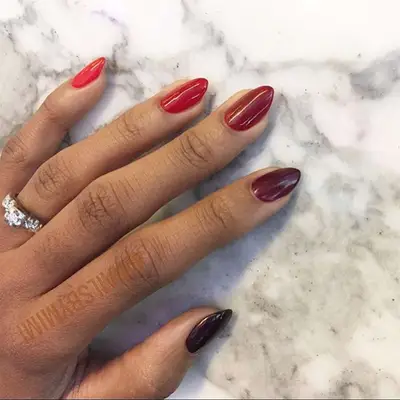 Red-to-black gradient manicured hand on marble background