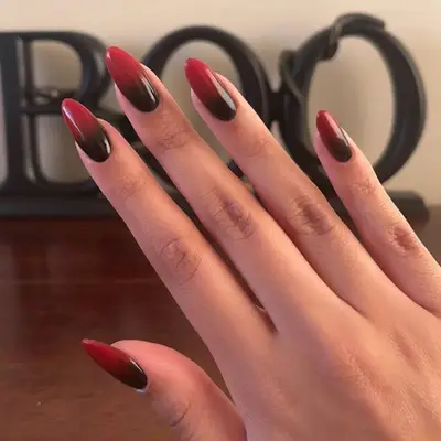 Close-up of black-to-red ombre manicure with extended oval tips