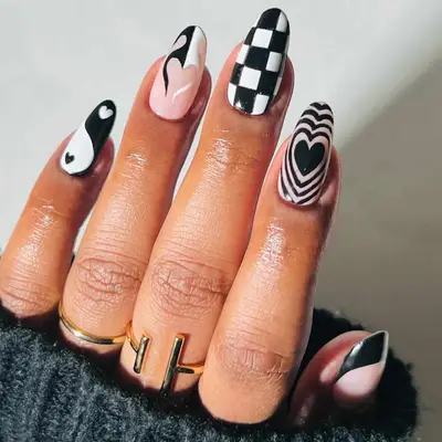 Black and white manicure with pulsating heart, flaming heart, yin/yang, checkerboard, and French tip designs