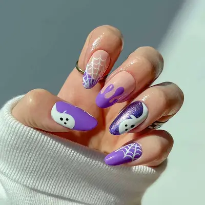 A mismatch purple manicure with ghost and spiderweb accents