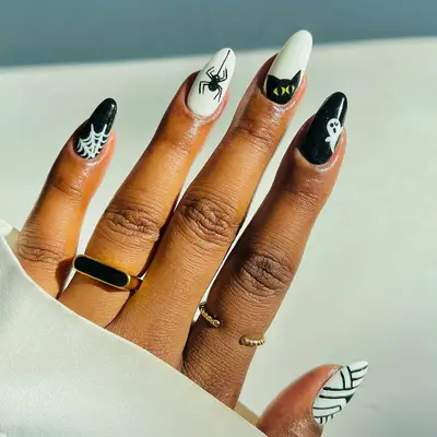 A mismatched monster manicure with a spiderweb pinky nail