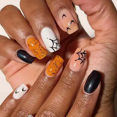 a mismatched manicure with spiderwebs on the middle fingers