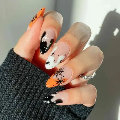 a swirly French manicure with mismatched halloween nail art, including webs