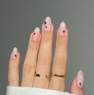 a spiderweb manicure with little spiders and hearts