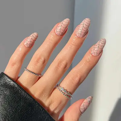 a spiderweb manicure with a nude base