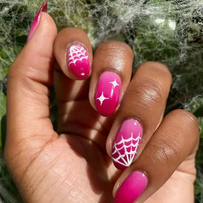 An ombre pink manicure with star and spidrweb details