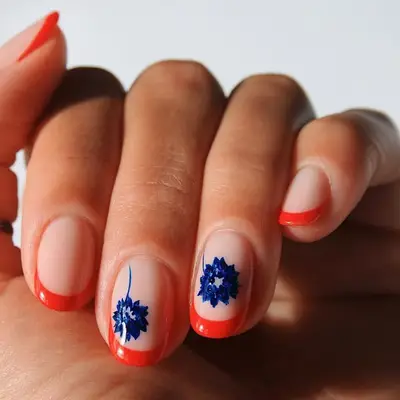 Red French tip manicure with blue flower designs on accent nails