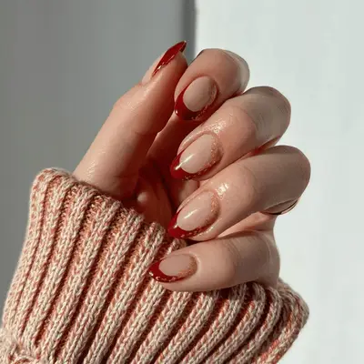 Alternating solid and French tip red manicure with gift bow accent nail with pearl