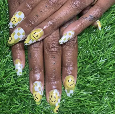 Almond-shaped nails with yellow smiley faces and white checkerboard design