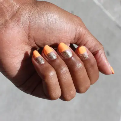 Half neon orange, half nude nails with metallic gold half moons