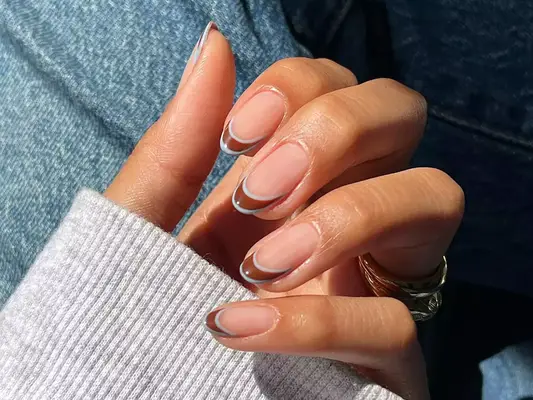 a brown french manicure with tips outlined in blue-gray