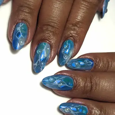Close-up of hands with manicured nails, featuring artistic blue designs