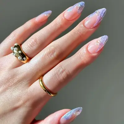 Hand with nail art featuring intricate patterns and two rings