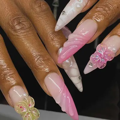 Close-up of hands displaying decorated long nails with various floral designs