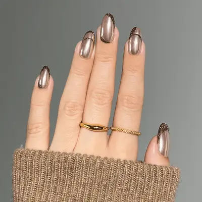 Bronze chrome nails with mocha-colored, glitter French tips.
