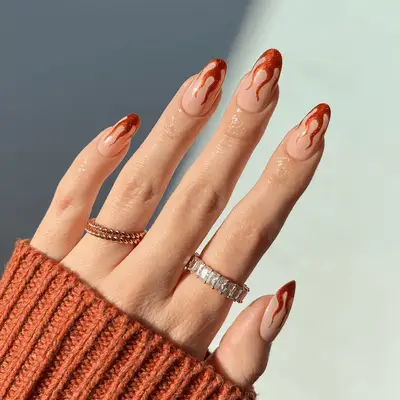 Nude nails with orange flame French tips.