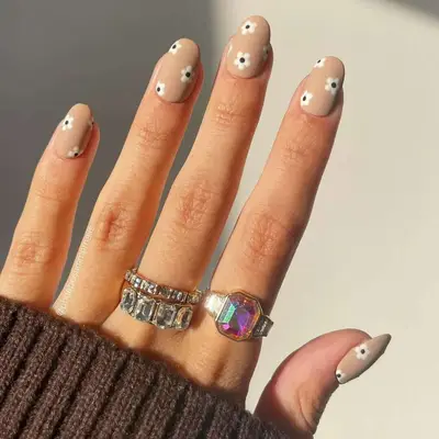 Bold daisy nail art on nude nails
