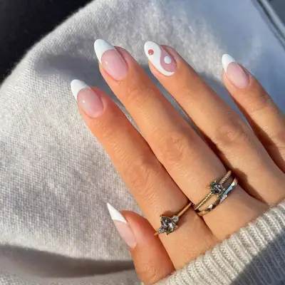 model with French tip nails and a yin and yang symbol on ring finger