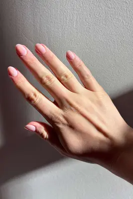 A hand with neatly manicured nails featuring a pink polish