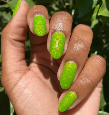 Sparkly bright green nail polish on short almond nails