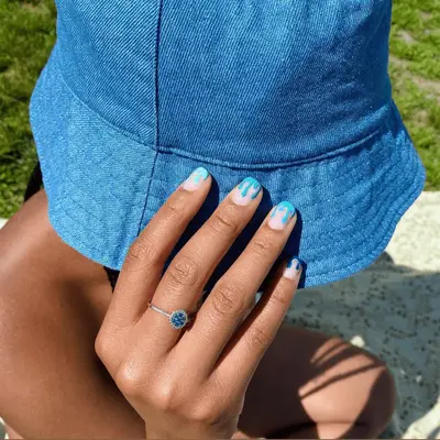 An orange matte manicure with drippy white polish with confetti