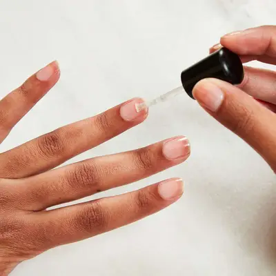 Woman applies a base coat to her nails