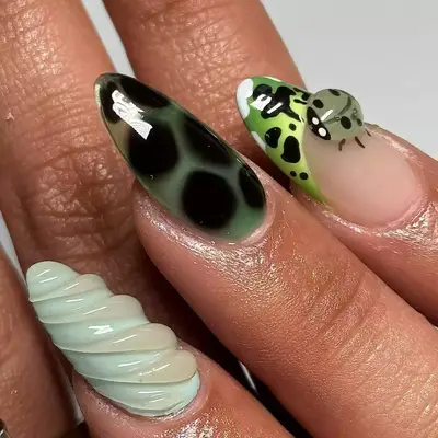 model with mix-and-match nails with 3D swirls, ladybug, spots, and green french tip