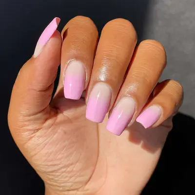 Hand with light pink ombre manicure.
