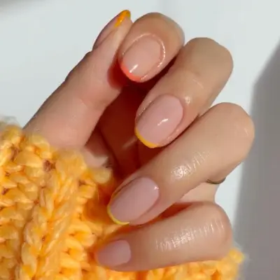 a micro french manicure in shades of orange and yellow