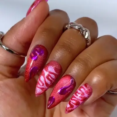 a velvet glass manicure with swirl designs in shades of red, pink, and purple