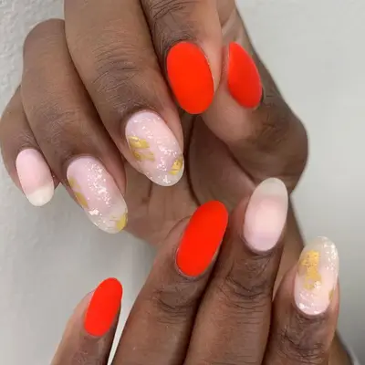 Red-orange nails with gold foil accents