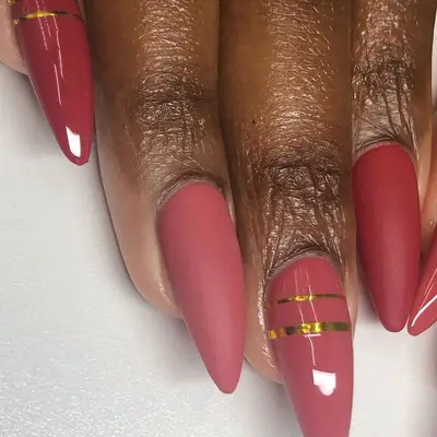 Muted red gradient nails with gold stripe details