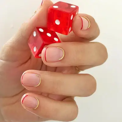 Minimalist nails with gold wire at cuticle and thin red French tip