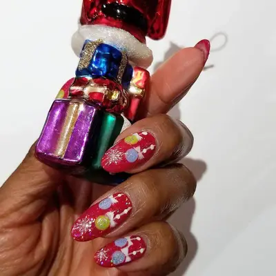 Red manicure with gold tinsel design and colorful ornaments