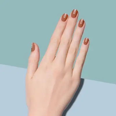 Medium brown matte nail design with light nude central strip and metallic dots