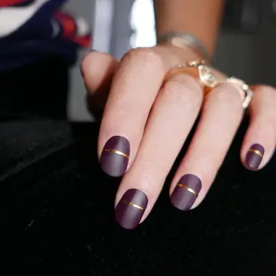 Dark wine-colored matte nails with gold horizontal single stripes