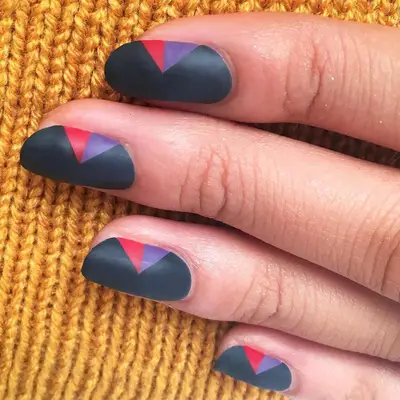 Charcoal matte nails with small red and purple triangle designs