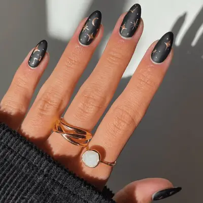 Almond-shaped nails with matte gray base and metallic gold celestial nail art