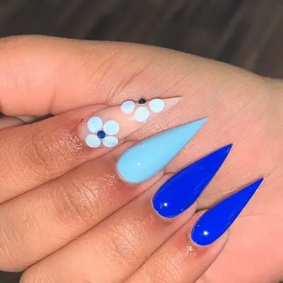 stilletto nails in shades of blue with one flower detailed nail