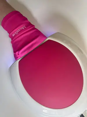 nails being cured under an LED light wearing pink gloves