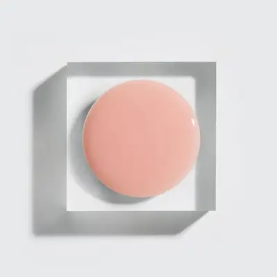 A small round container or surface in a square frame, likely cosmetic-related