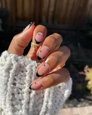 A French manicure with black tips, decorated with tiny silver pearls.