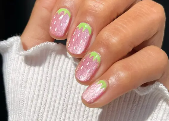 A hand with fingernails painted in a strawberry-themed design
