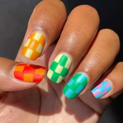 Model with checkered nails in bright, rainbow colors