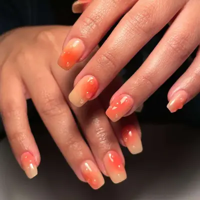 Model with peach and orange nails with clear 3D drops