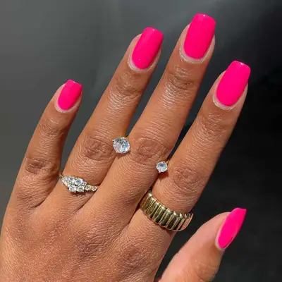 Model with hot pink nails in a short, square shape