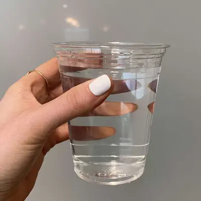 Hand holding a clear cup of water.