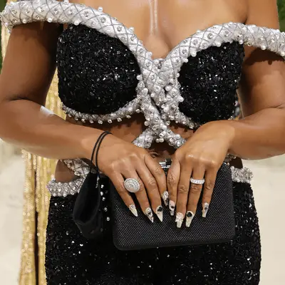 Taraji poses with hands open in front of her face with black bejeweled nails